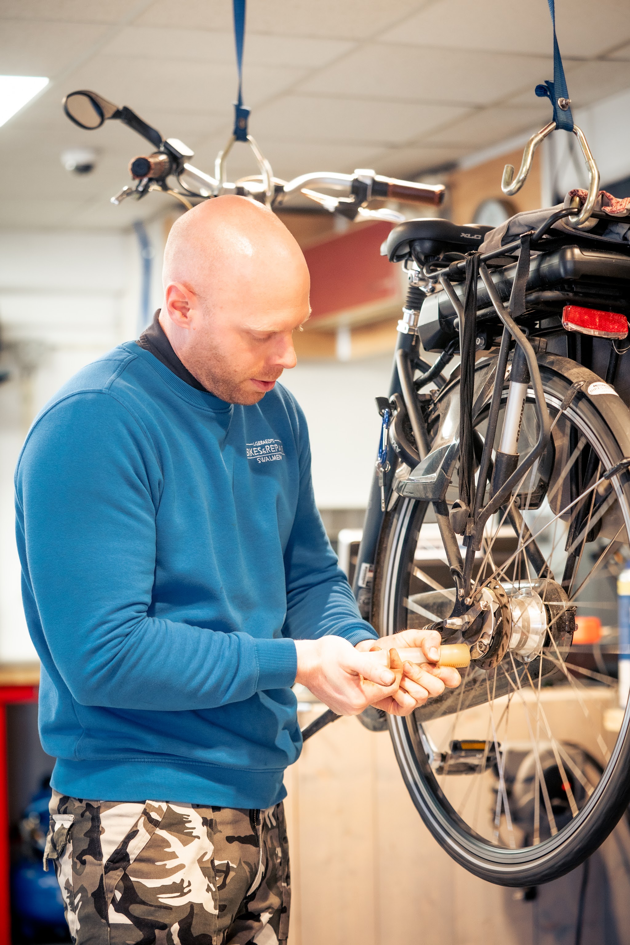 Jan servicet de naaf van een E-Bike die aan een ophangband hangt