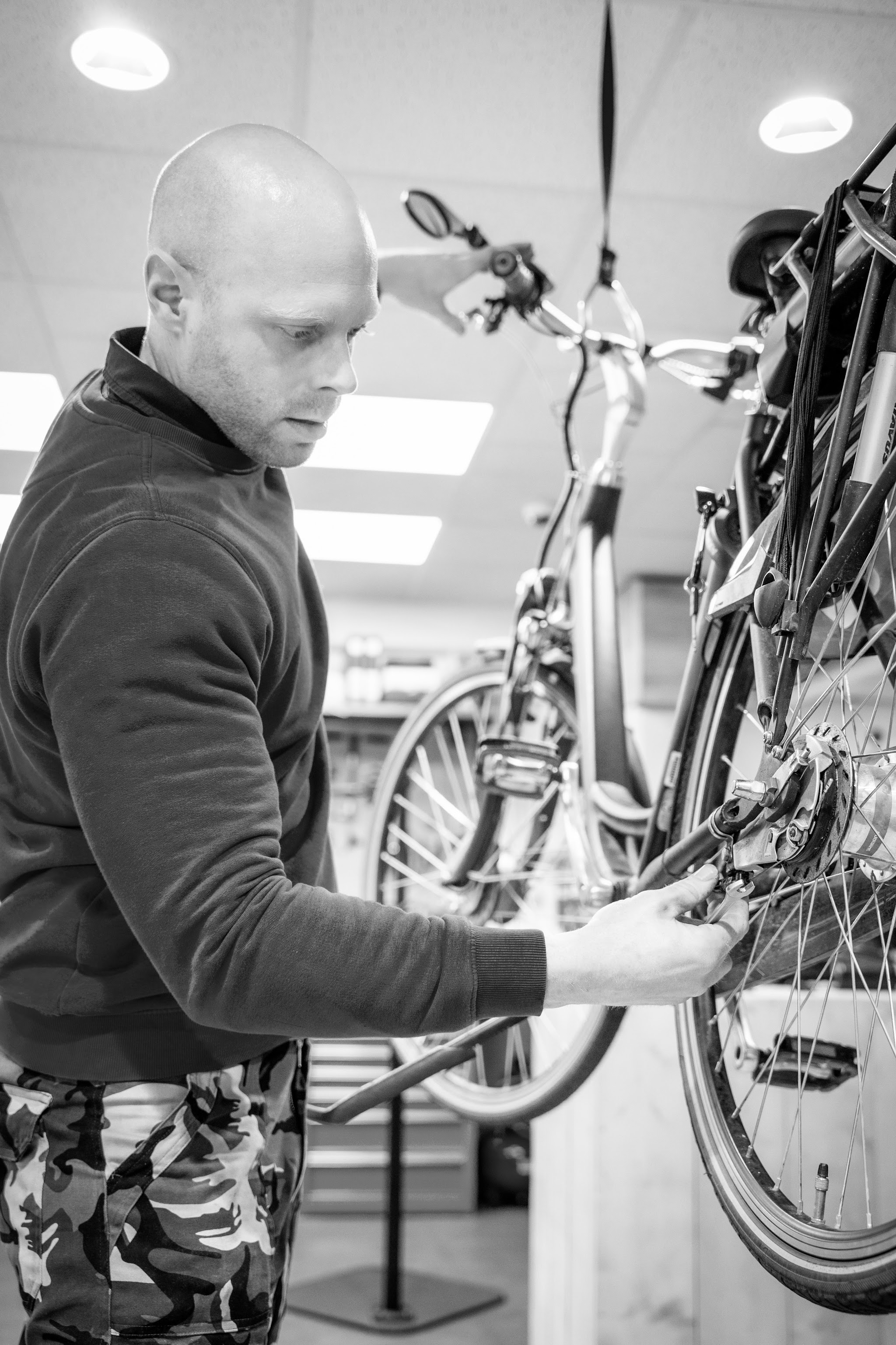 Zwart-witportret van Jan Geraedts terwijl hij aan een wiel werkt